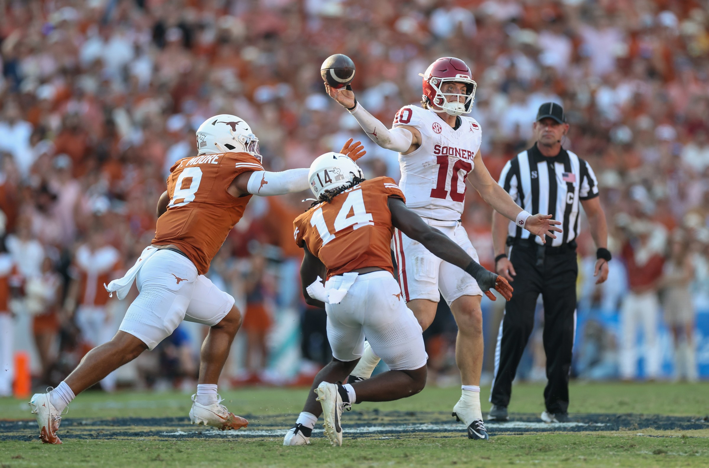 DALLAS, TEXAS - OCTOBER 11: John Mateer #10 of the Oklahoma Sooners looks to pass under pressure by Trey Moore #8 of the Texas Longhorns and Brad Spence #14 in the fourth quarter at Cotton Bowl on October 11, 2025 in Dallas, Texas. (Photo by Tim Warner/Getty Images)