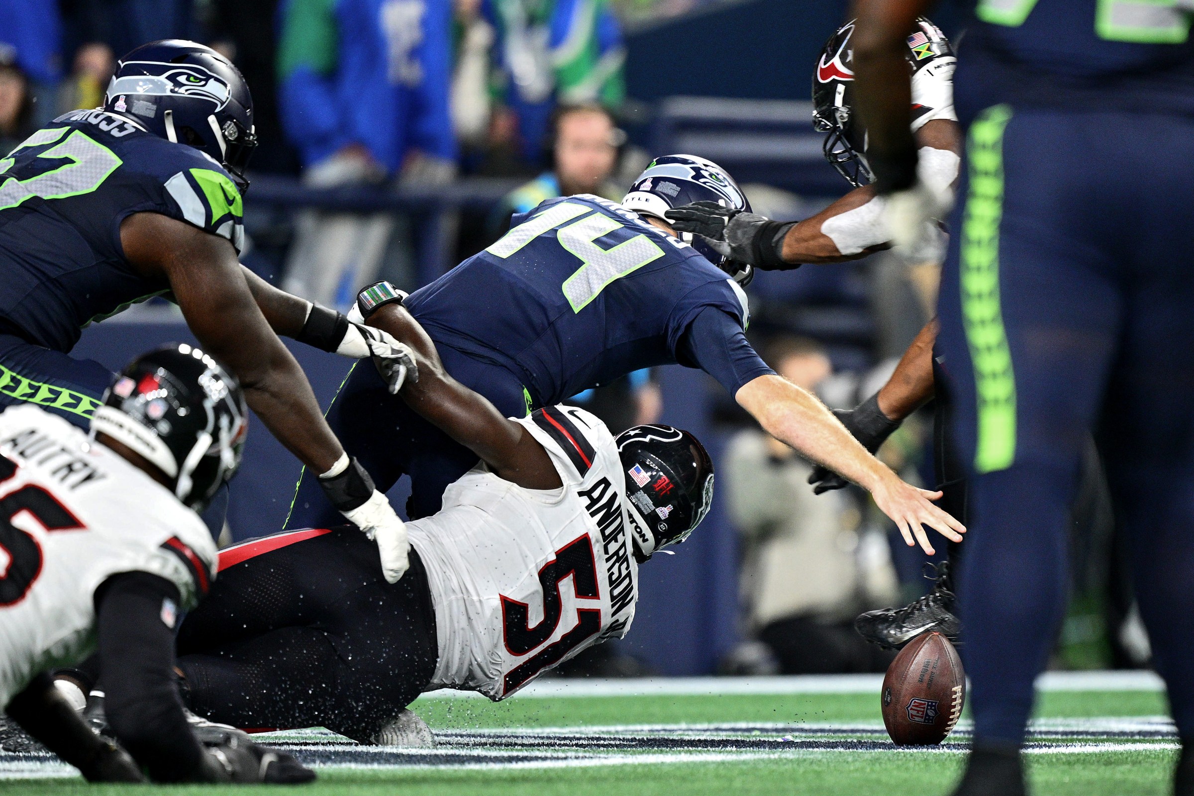 SEATTLE, WASHINGTON - OCTOBER 20: Sam Darnold #14 of the Seattle Seahawks fumbles the ball in the end zone as Will Anderson Jr. #51 of the Houston Texans tackles him during the third quarter at Lumen Field on October 20, 2025 in Seattle, Washington. (Photo by Jane Gershovich/Getty Images)