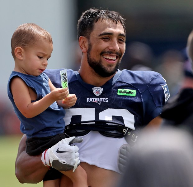 New England Patriots linebacker Christian Elliss #53 holds a little boy after training camp at Gillette Stadium. (Photo By Matt Stone/Boston Herald)