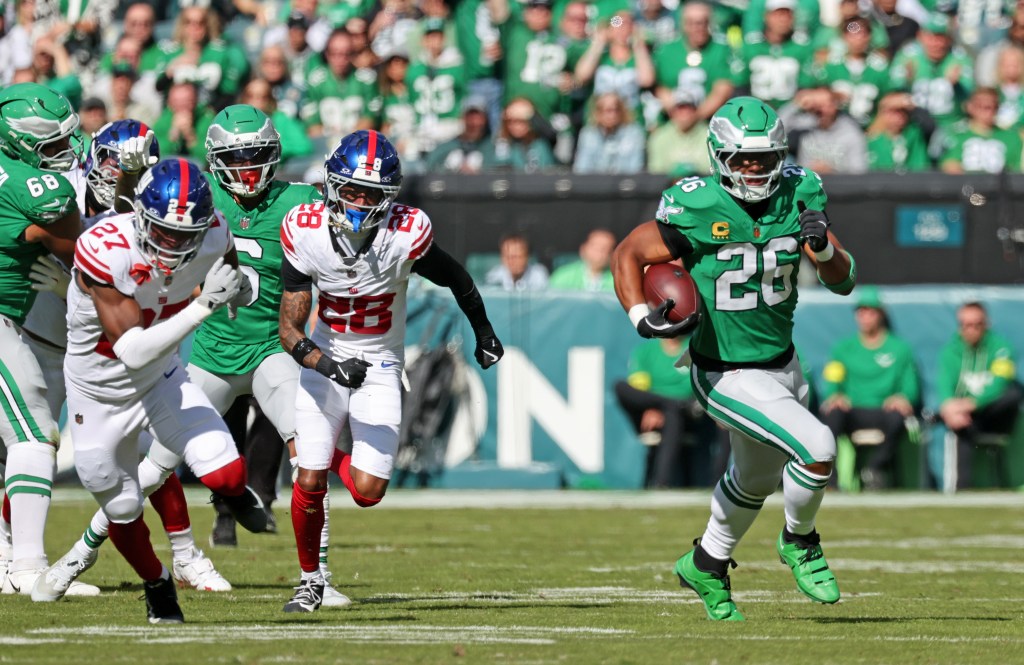 Philadelphia Eagles running back Saquon Barkley #26 breaks away from New York Giants safety Tyler Nubin #27 and New York Giants cornerback Cor'Dale Flott #28 and runs the ball in for a touchdown during the first quarter.