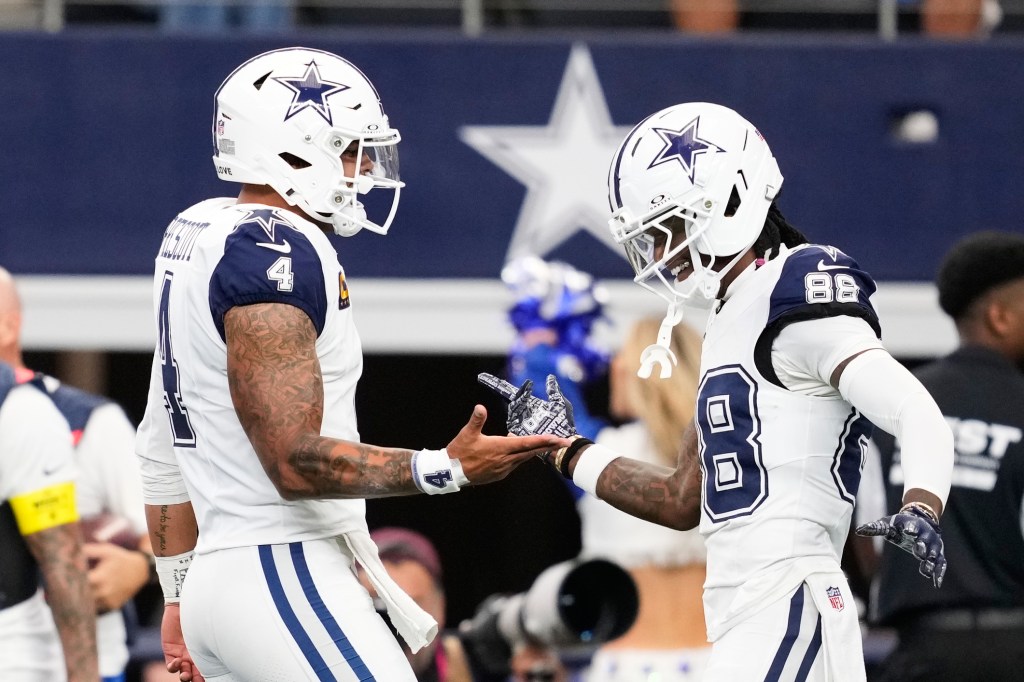 Cowboys players Dak Prescott (4) and CeeDee Lamb (88) greet each other on the field.