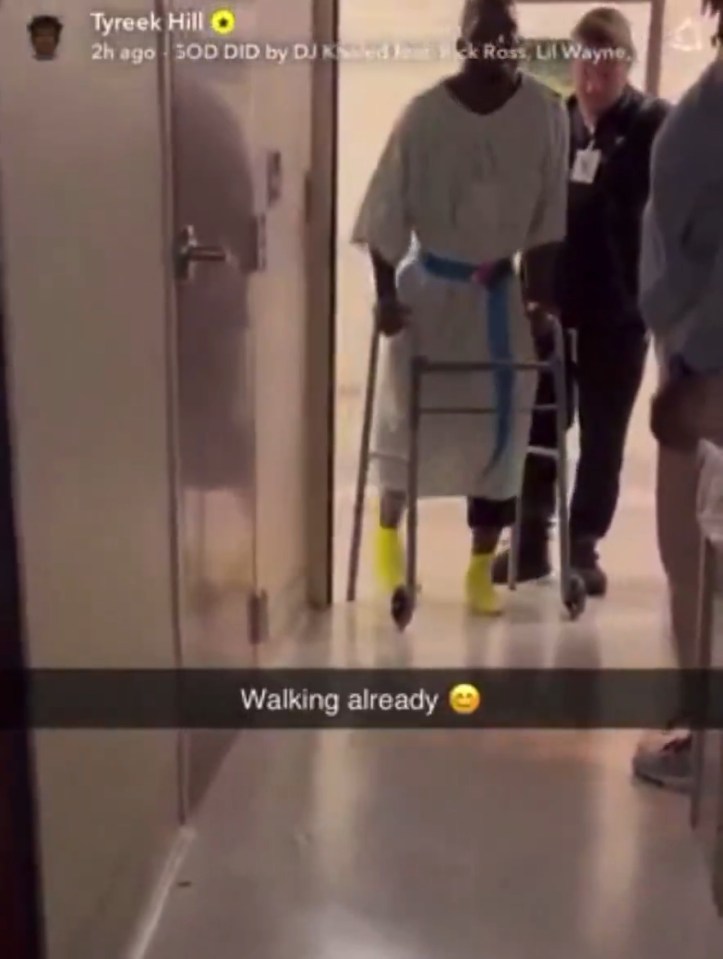 Tyreek Hill walking in a hospital gown with a walker.