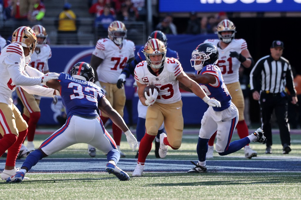 Christian McCaffrey #23 of the San Francisco 49ers running with the ball as Dru Phillips #22 of the New York Giants chases him.