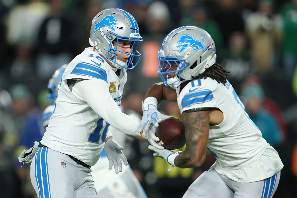 Jared Goff #16 handing the ball to Jahmyr Gibbs #0 during a Detroit Lions vs. Philadelphia Eagles game.