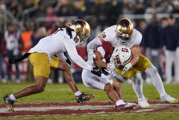Stanford wide receiver Marcus Brown, center, is tackled by Notre Dame safety Jalen Stroman, left, and linebacker Drayk Bowen during the first half of an NCAA college football game, Saturday, Nov. 29, 2025, in Stanford, Calif. (AP Photo/Godofredo A. Vásquez)
