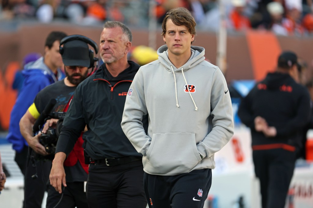Joe Burrow, quarterback for the Cincinnati Bengals, wearing a grey hoodie and black sweatpants, walks on the sidelines during a game against the New York Jets.