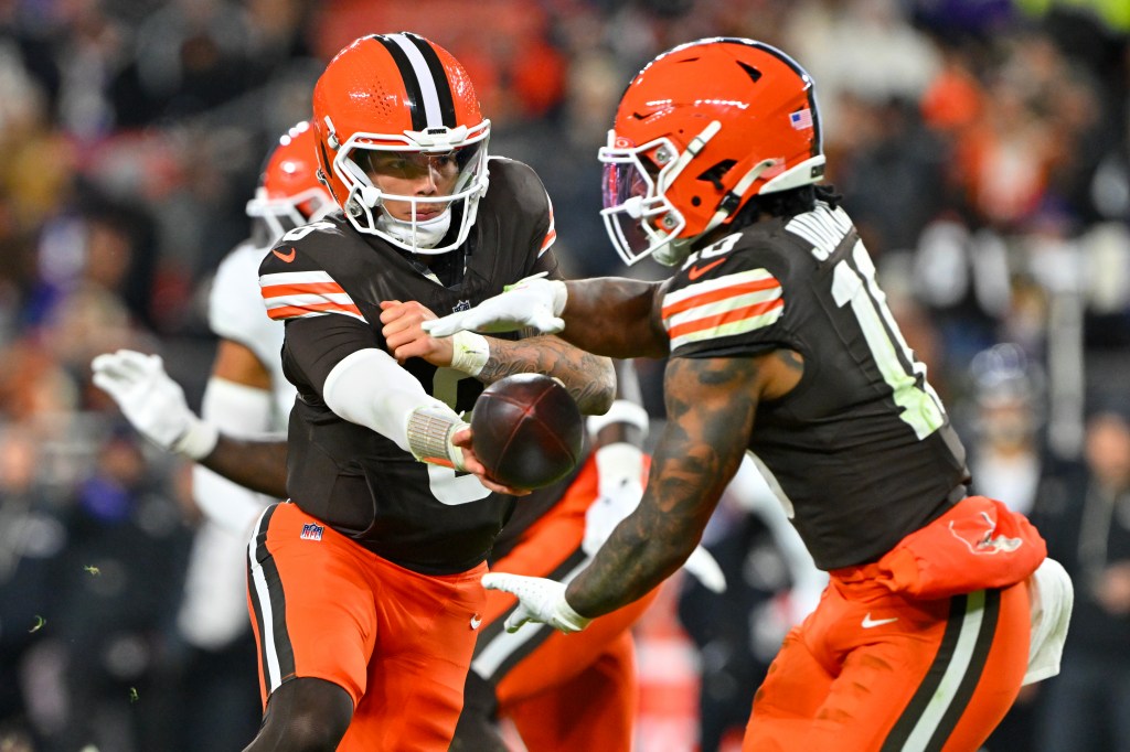 Cleveland Browns players in brown and orange uniforms exchange a handoff during a game.