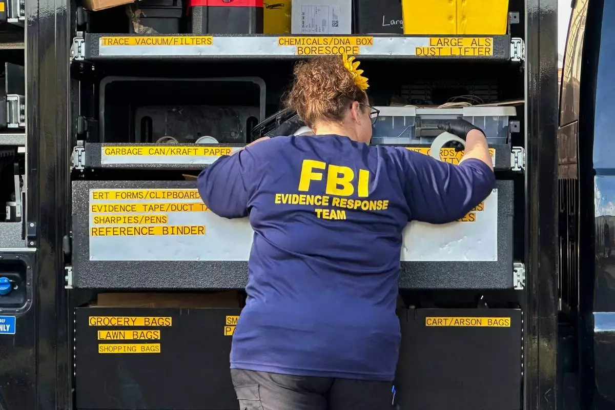 An FBI agent stands by an Evidence Response Team truck outside a home in a Dearborn, Mich., neighborhood on Friday, Oct. 31, 2025. (AP Photo/Mike Householder)
