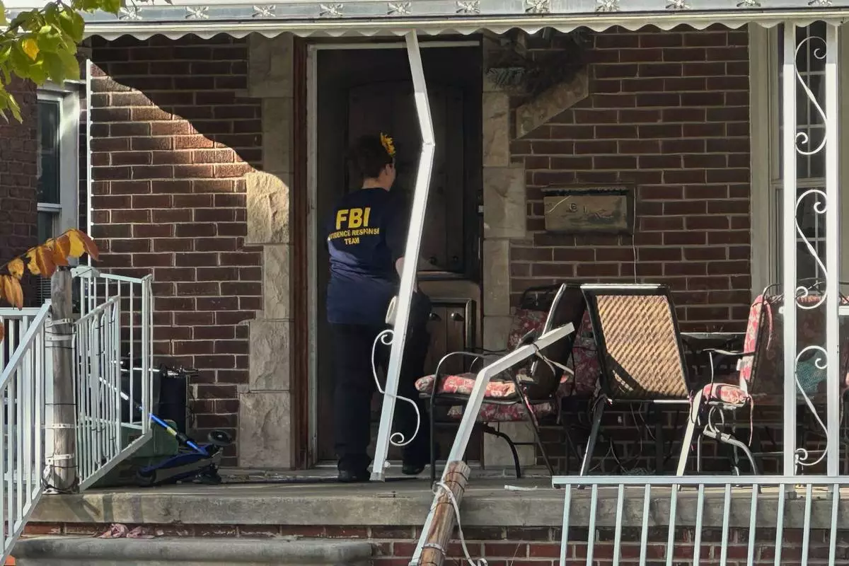 An FBI agent enters a home in a Dearborn, Mich., neighborhood on Friday, Oct. 31, 2025. (AP Photo/Mike Householder)