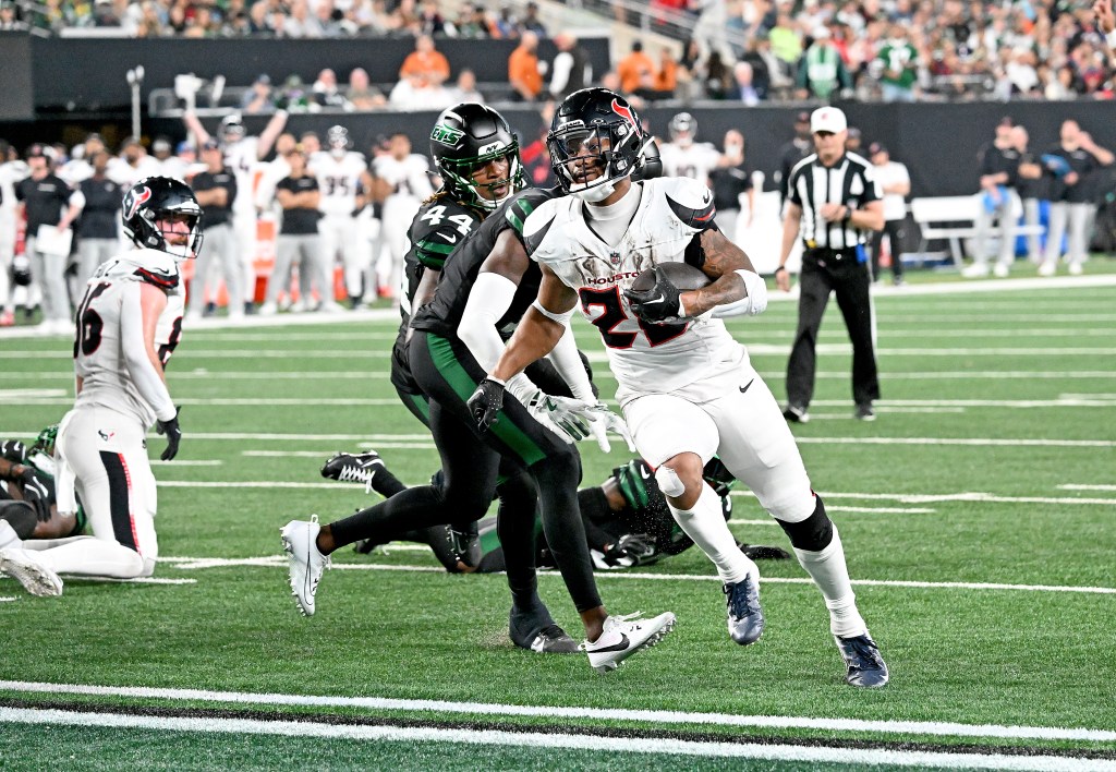 Houston Texans player Joe Mixon, number 28, runs with the football while a New York Jets player, number 44, attempts to tackle him.