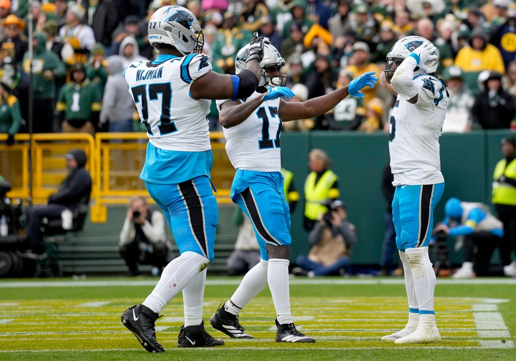 Carolina Panthers players Rico Dowdle (5), Yosh Nijman (77), and Xavier Legette (17) celebrate a touchdown.