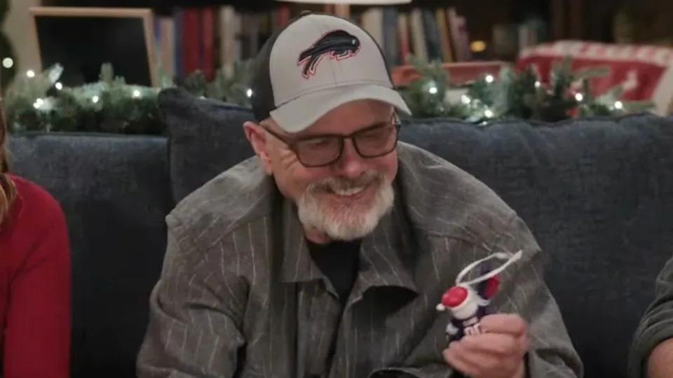  Man in a Bills cap holding an ornament. 