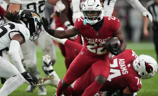 Arizona Cardinals running back Michael Carter (22) runs the ball against Jacksonville Jaguars safety Antonio Johnson (26) during the first half of an NFL football game Sunday, Nov. 23, 2025, in Glendale, Ariz. (AP Photo/Ross D. Franklin)