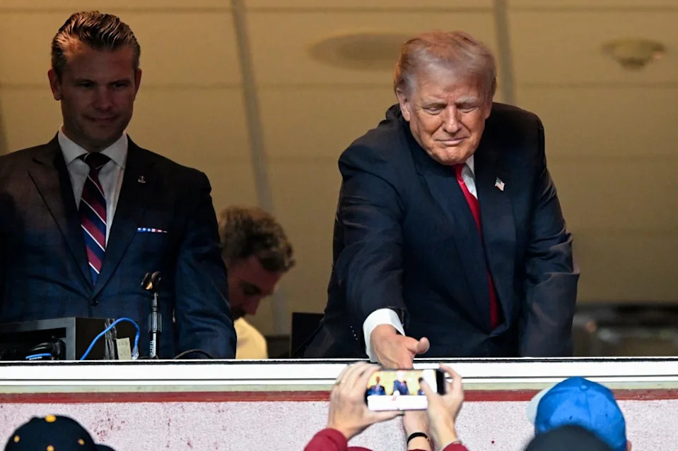 Secretary of War Pete Hegseth (left) watches U.S. President Donald Trump shake the hand of a young fan as he attends the Lions’ Week 10 road win over the Commanders. Getty Images