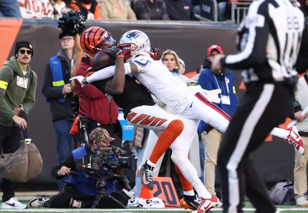 Cincinnati Bengals wide receiver Tee Higgins (5) almost makes a one handed catch but gets injured on the play as New England Patriots cornerback Carlton Davis III (7) defends during an NFL football game Sunday, Nov 23, 2025, in Cincinnati, OH (AP Photo/Peter Joneleit)