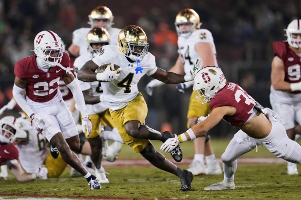 Notre Dame running back Jeremiyah Love (4) stiff arms Stanford safety Mitch Leigber (32) during the first half of an NCAA college football game, Saturday, Nov. 29, 2025, in Stanford, Calif. (AP Photo/Godofredo A. Vásquez)