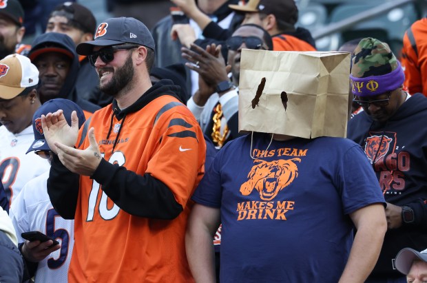 A Bengals fan celebrates while a Bears fan wears a...