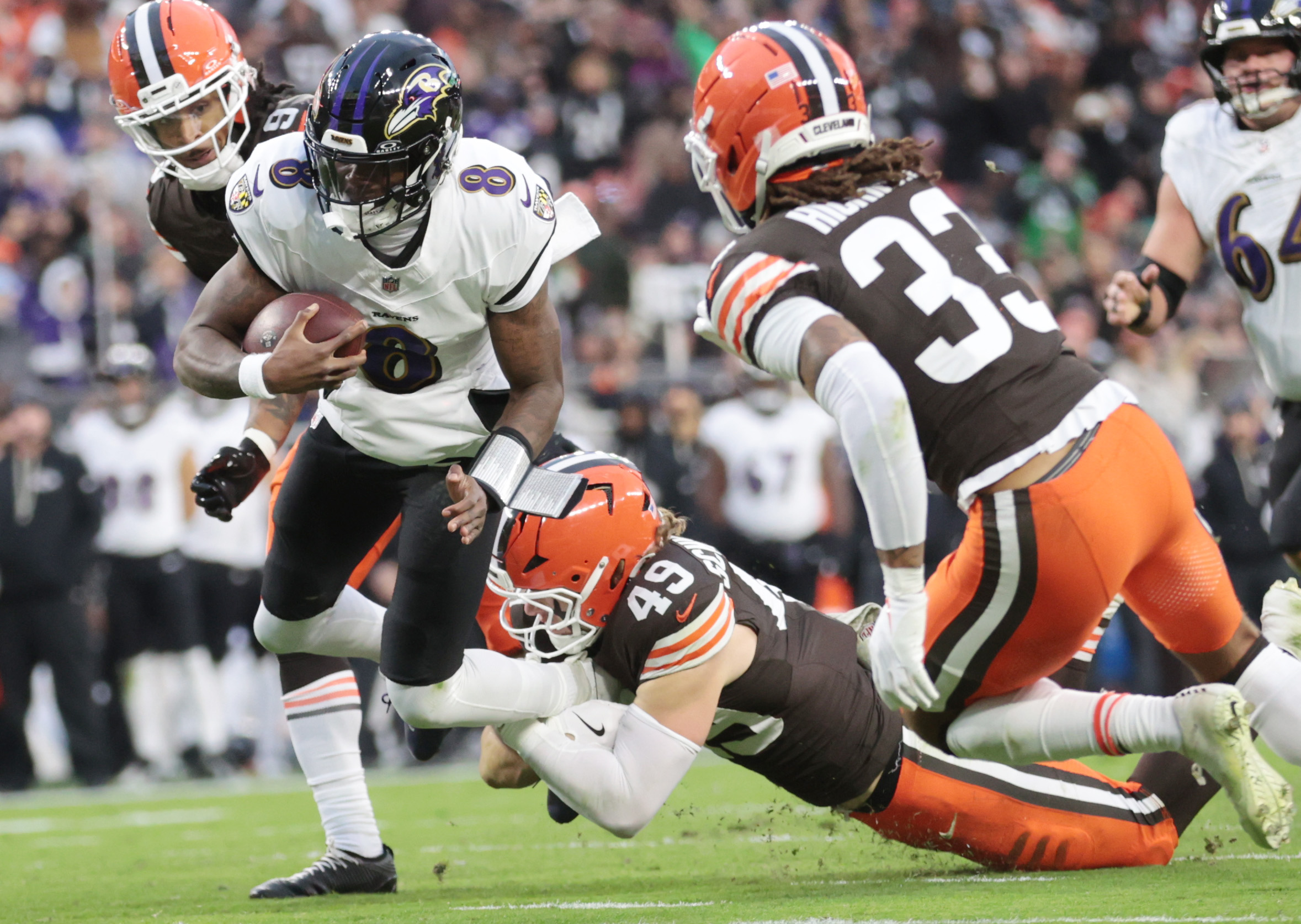 Baltimore Ravens quarterback Lamar Jackson fights yards on a keeper as he is tackled by Cleveland Browns linebacker Carson Schwesinger in the first half.  