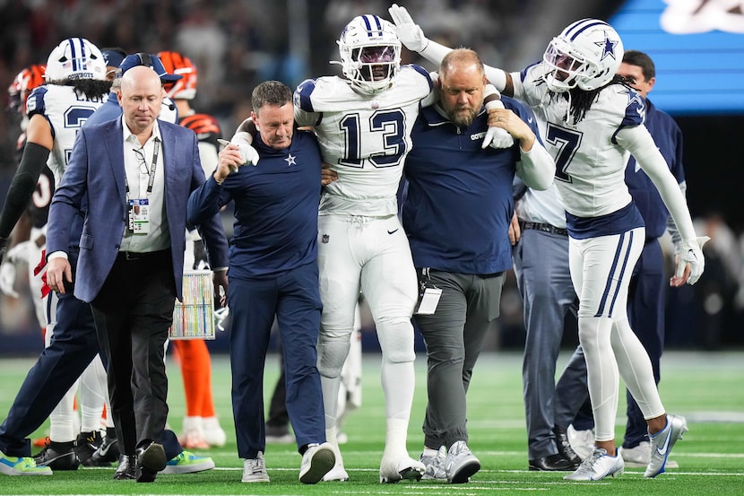 Dallas Cowboys linebacker DeMarvion Overshown (13) is helped off the field after being...