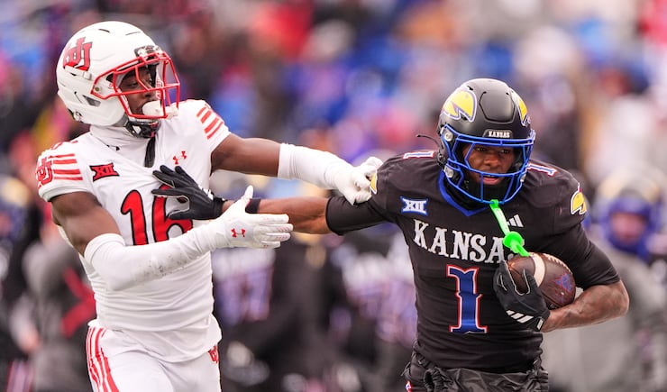 Kansas running back Johnny Thompson Jr. (1) runs the ball under pressure from Utah cornerback Blake Cotton (16) during game Friday, Nov. 28, 2025, in Lawrence, Kan. (AP Photo/Charlie Riedel)