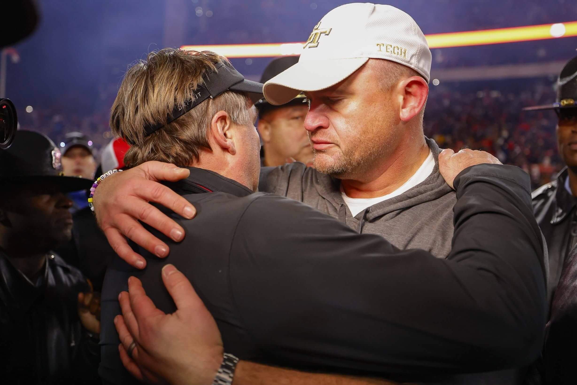 Georgia coach Kirby Smart, in visor and black jacket, embraces Georgia Tech coach Brent Key, in white ballcap, after last season's eight-overtime game.