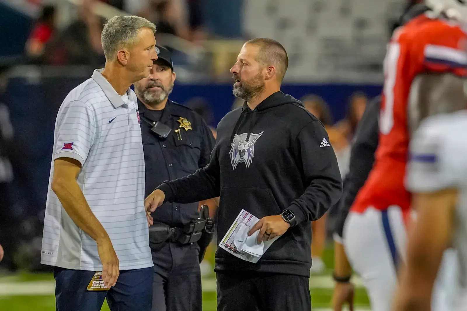 College football head coach Brent Brennan of the Arizona Wildcats and Head coach Mickey Mental of the Weber State Wildcats