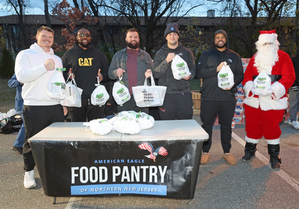 Giants offensive linemen (left-right): John Michael Schmitz Jr., Josh Ezeudu, Austin Schlottmann, Reid Holskey, Jermaine Eluemunor, and Santa, handing out turkeys at the American Eagle Food Pantry in Lodi, N.J.