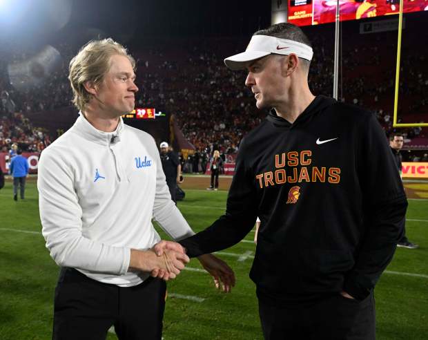 Coach Jerry Neuheisel of the UCLA Bruins shakes hands with...