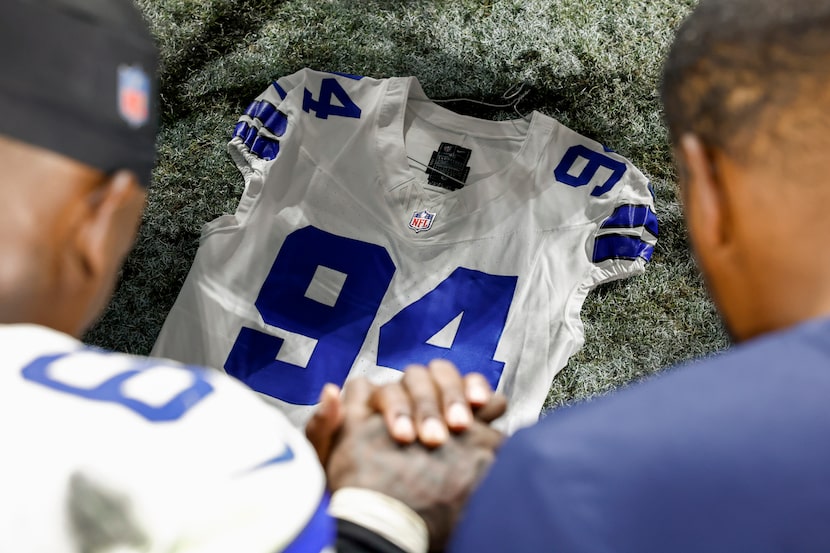 Dallas Cowboys and Las Vegas Raiders players pray over a Marshawn Kneeland jersey after an...