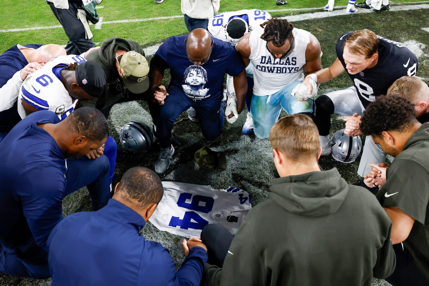 Dallas Cowboys and Las Vegas Raiders players pray over a Marshawn Kneeland jersey after an...