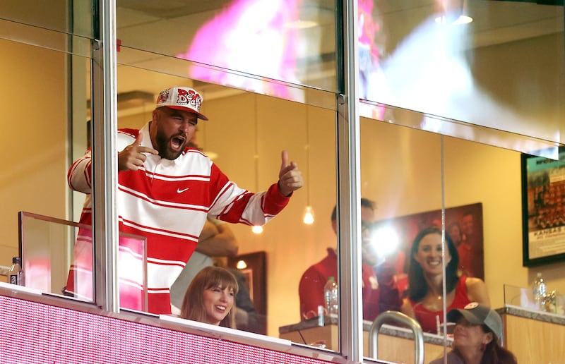 Travis Kelce of the Kansas City Chiefs reacts as fiancee Taylor Swift smiles while watching from a suite during the second half of the game between the Cincinnati Bearcats and the Nebraska Cornhuskers at Arrowhead Stadium on August 28, 2025 in Kansas City, Missouri.