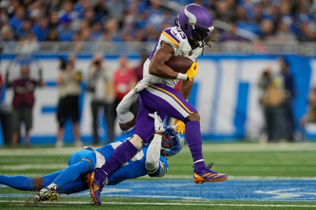 Minnesota Vikings running back Aaron Jones (33) runs with the football as Detroit Lions safety Thomas Harper (12) tries to tackle during the first half of an NFL football game Sunday, Nov. 2, 2025, in Detroit. (AP Photo/Ryan Sun)