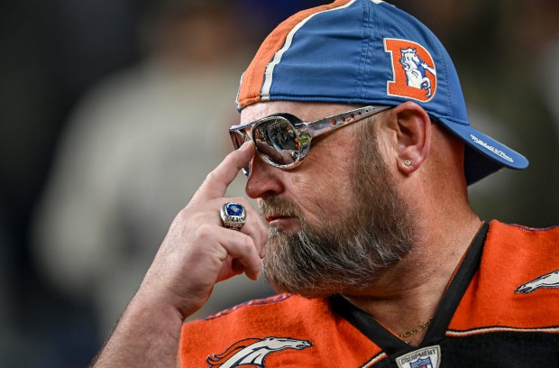 A Denver Broncos fan pushes up his shades during the...