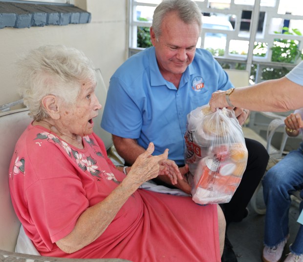 Former Miami Dolphin John Offerdahl, delivers a week's worth of meals to Barbara Mundy, 93, in her Deerfield Beach home on Thursday, Nov. 20, 2025. The delivery is part of Offerdahl's foundation Hands-Off Meals delivery to seniors. (Carline Jean/South Florida Sun Sentinel) 
