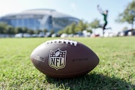 A football rests in the grass as fans tailgate before an NFL football game between the...