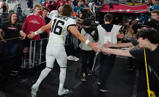 Jacksonville Jaguars quarterback Trevor Lawrence greets fans as he leaves the field after an NFL football game against the Arizona Cardinals Sunday, Nov. 23, 2025, in Glendale, Ariz. (AP Photo/Ross D. Franklin)
