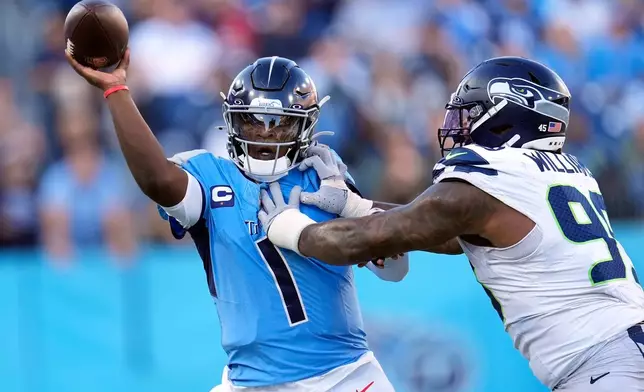 Tennessee Titans quarterback Cam Ward (1) gets a pass away as he is pressured by Seattle Seahawks defensive end Leonard Williams (99) during the second half of an NFL football game Sunday, Nov. 23, 2025, in Nashville, Tenn. (AP Photo/George Walker IV)