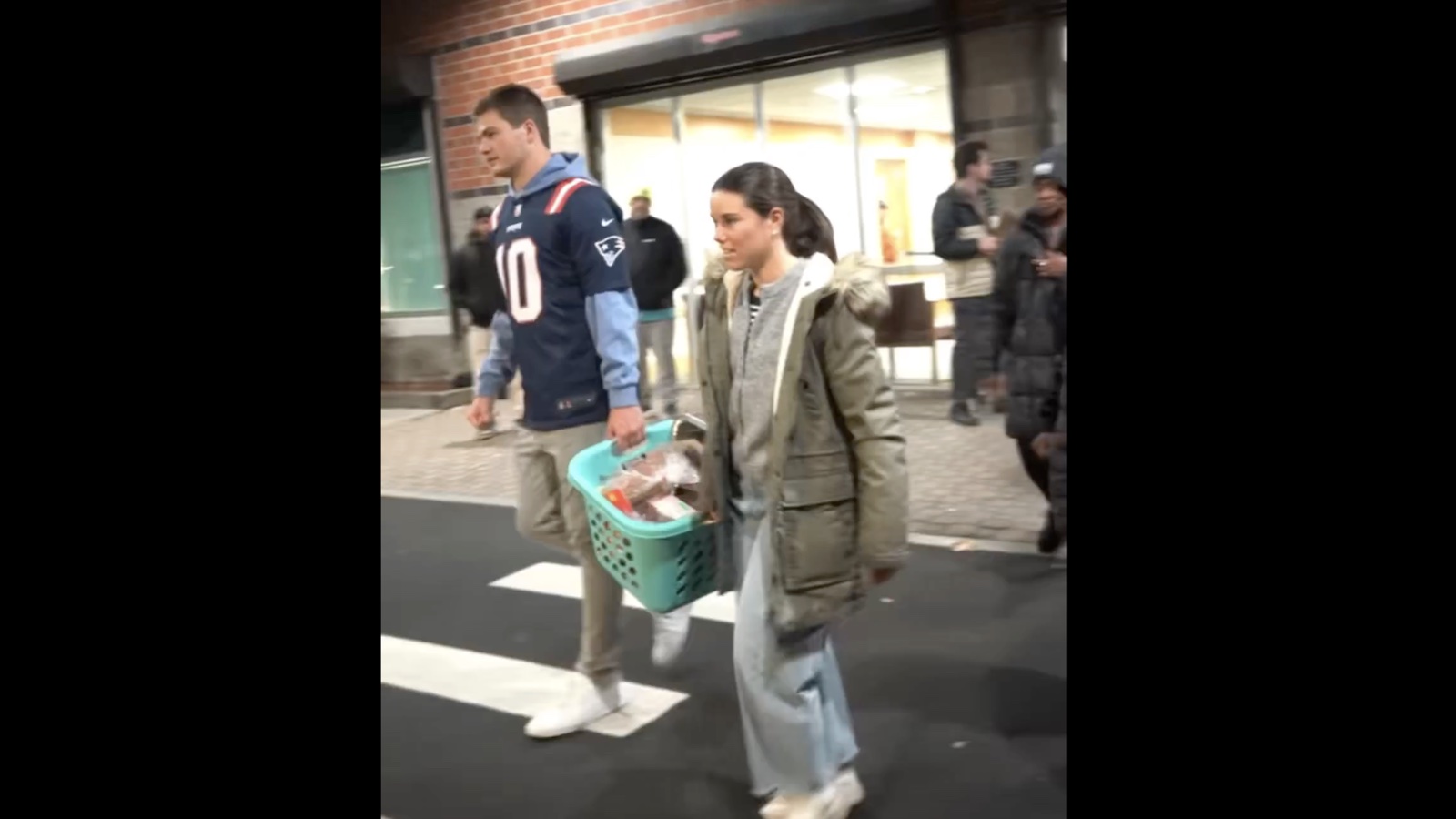 Drake Maye and his wife, Ann Michael, carrying donation baskets during a Patriots Thanksgiving charity event