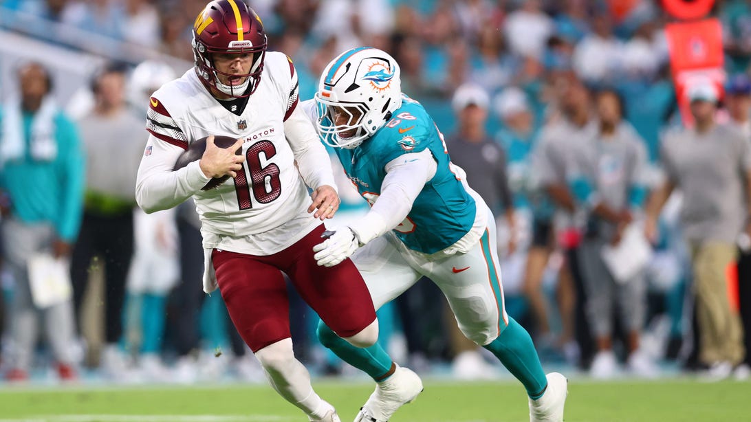 MIAMI GARDENS, FLORIDA - AUGUST 17: Quinton Bell #56 of the Miami Dolphins tackles Jeff Driskel #16 of the Washington Commanders during the second quarter of a preseason game at Hard Rock Stadium on August 17, 2024 in Miami Gardens, Florida.