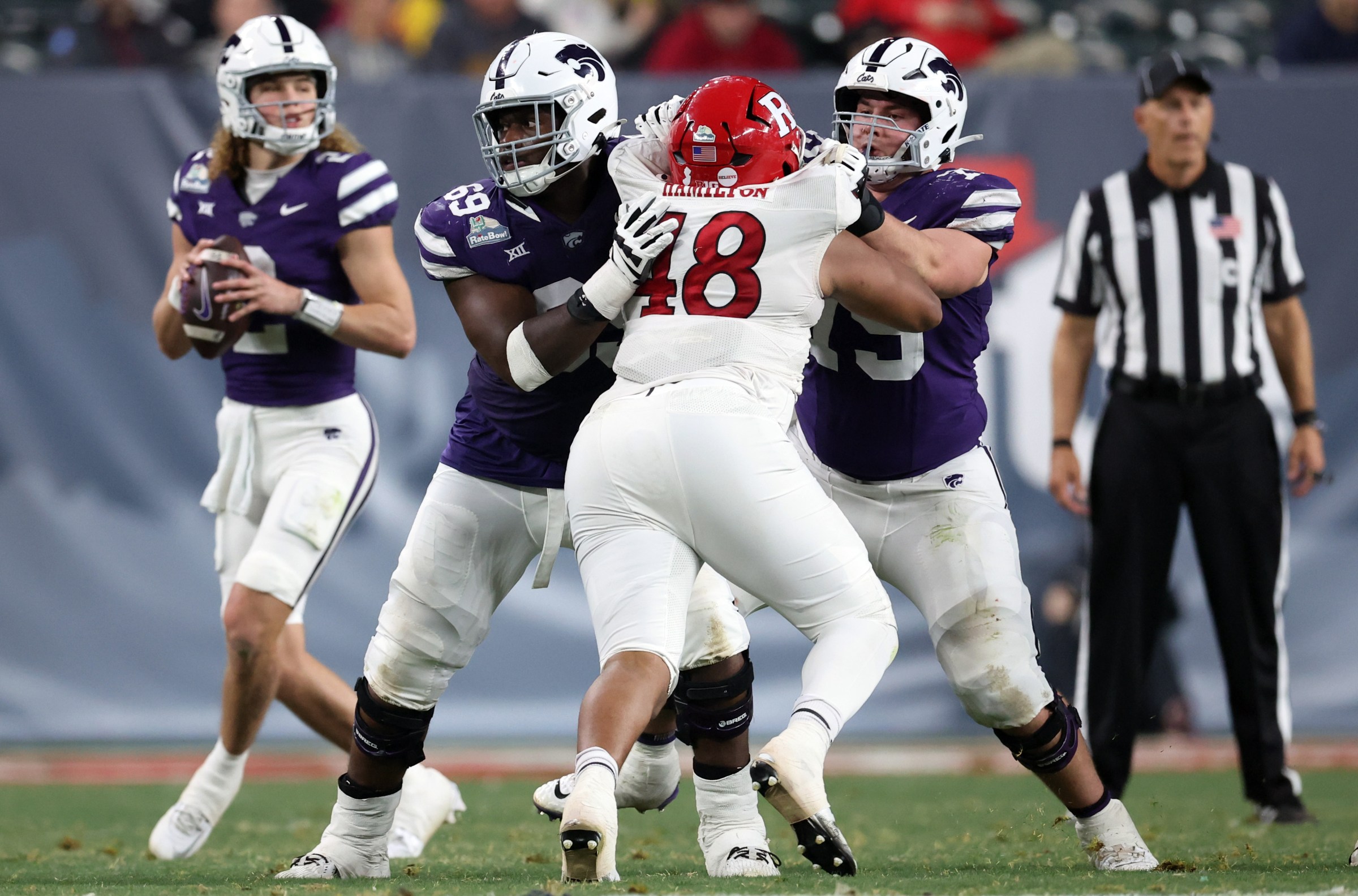 PHOENIX, ARIZONA - DECEMBER 26: Offensive lineman Taylor Poitier #69 of the Kansas State Wildcats and offensive lineman Sam Hecht #75 block defensive lineman Kyonte Hamilton #48 of the Rutgers Scarlet Knights during the Rate Bowl at Chase Field on December 26, 2024 in Phoenix, Arizona. The Wildcats defeated the Scarlet Knights 44-41. (Photo by Chris Coduto/Getty Images)