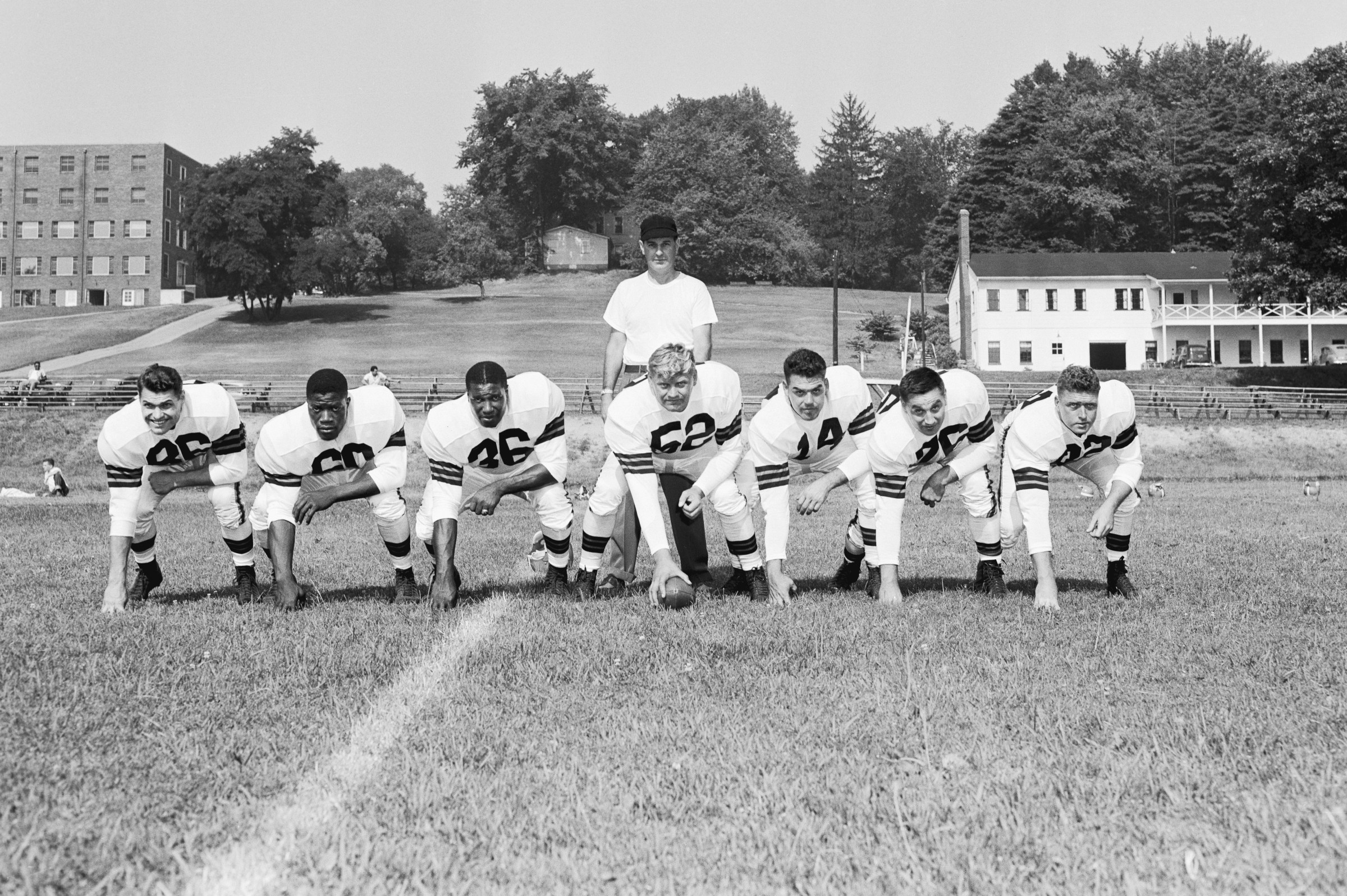 Left to right: Dante Lavelli, end; Bill Willis, guard; Marion Motley, fullback; Frank Gatski, center; Otto Graham, quarterback; Lou Groza, tackle and George Young, end. Browns head coach Paul Brown (standing)