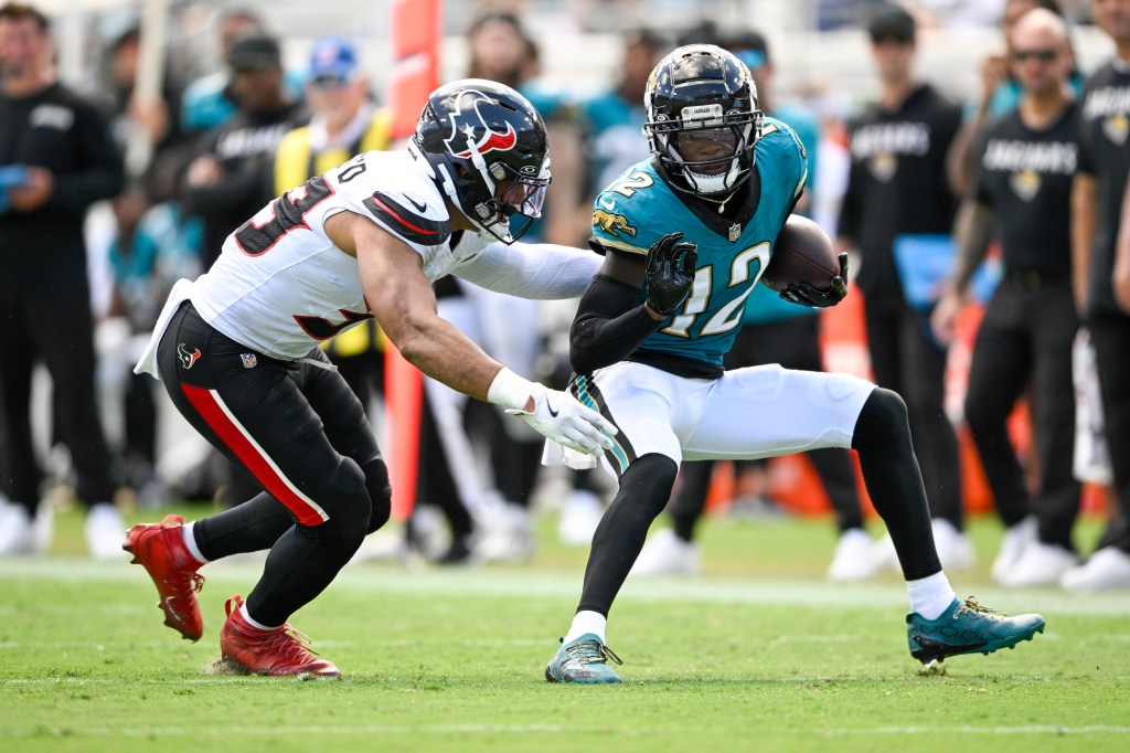 Jacksonville Jaguars wide receiver Travis Hunter tries to avoid a tackle by Houston Texans linebacker Henry To'Oto'O.