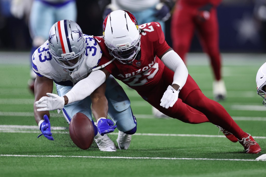 Javonte Williams of the Dallas Cowboys and Denzel Burke of the Arizona Cardinals battle for the football.