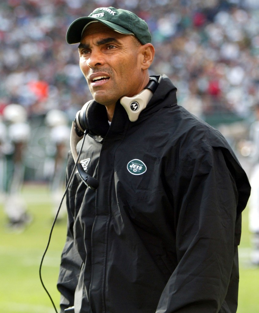 Herm Edwards, coach of the New York Jets, wearing a green cap and black jacket with a Jets logo.