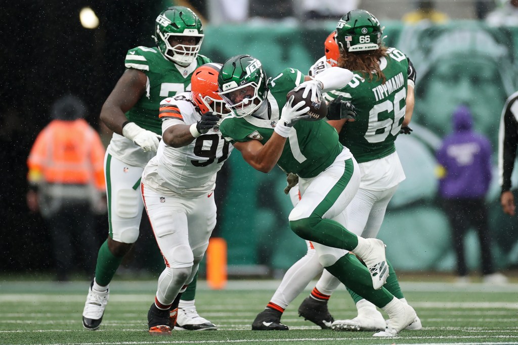 Justin Fields of the New York Jets running with the ball against Alex Wright of the Cleveland Browns.