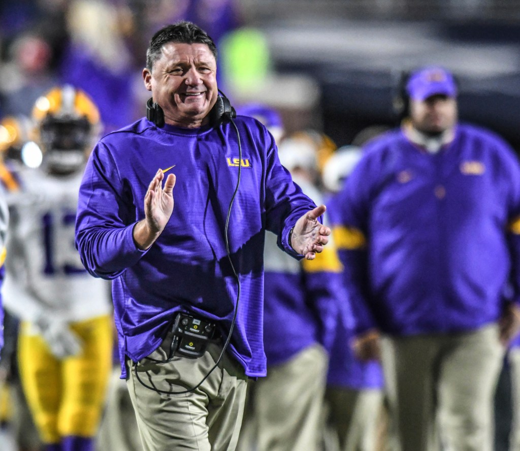 LSU coach Ed Orgeron smiles and claps during a game.