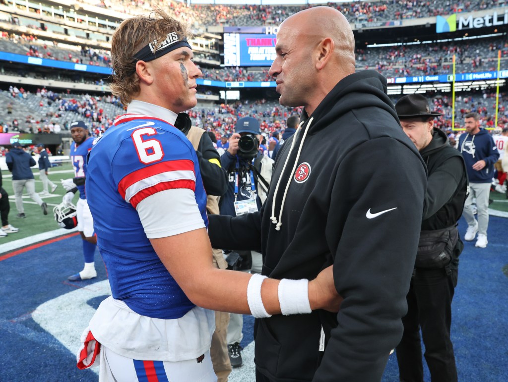 San Francisco 49ers defensive coordinator Robert Saleh hugging New York Giants quarterback Jaxson Dart #6 on the field.