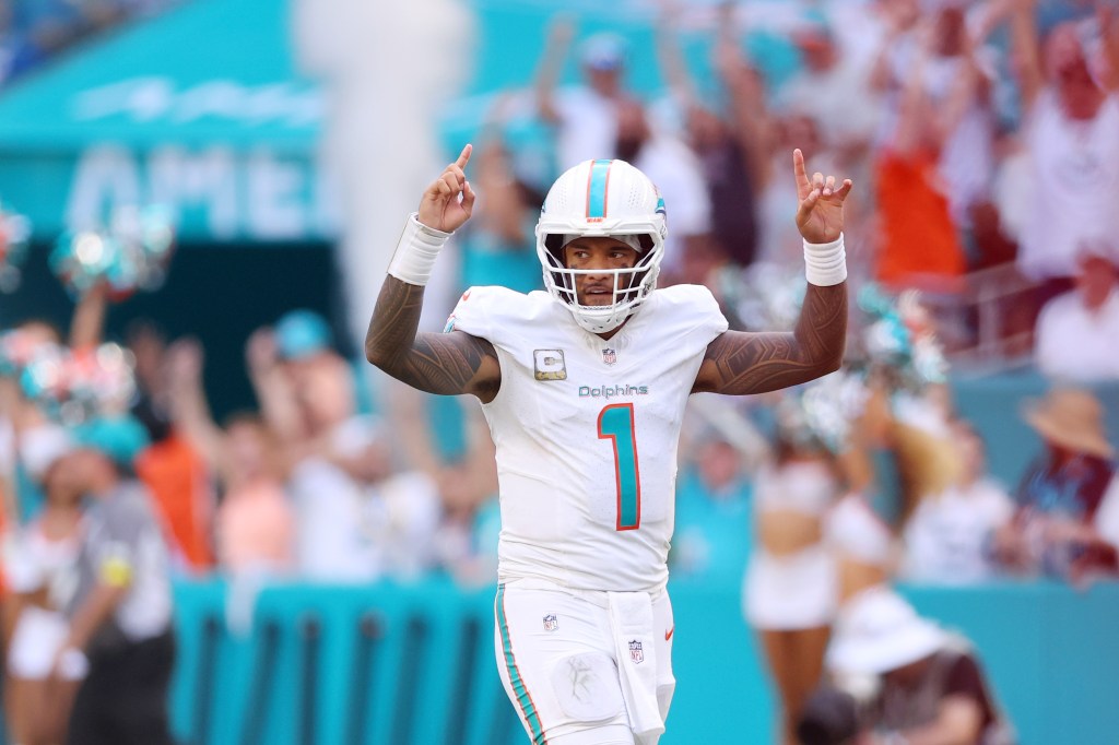 Miami Dolphins quarterback Tua Tagovailoa celebrating with hands raised.