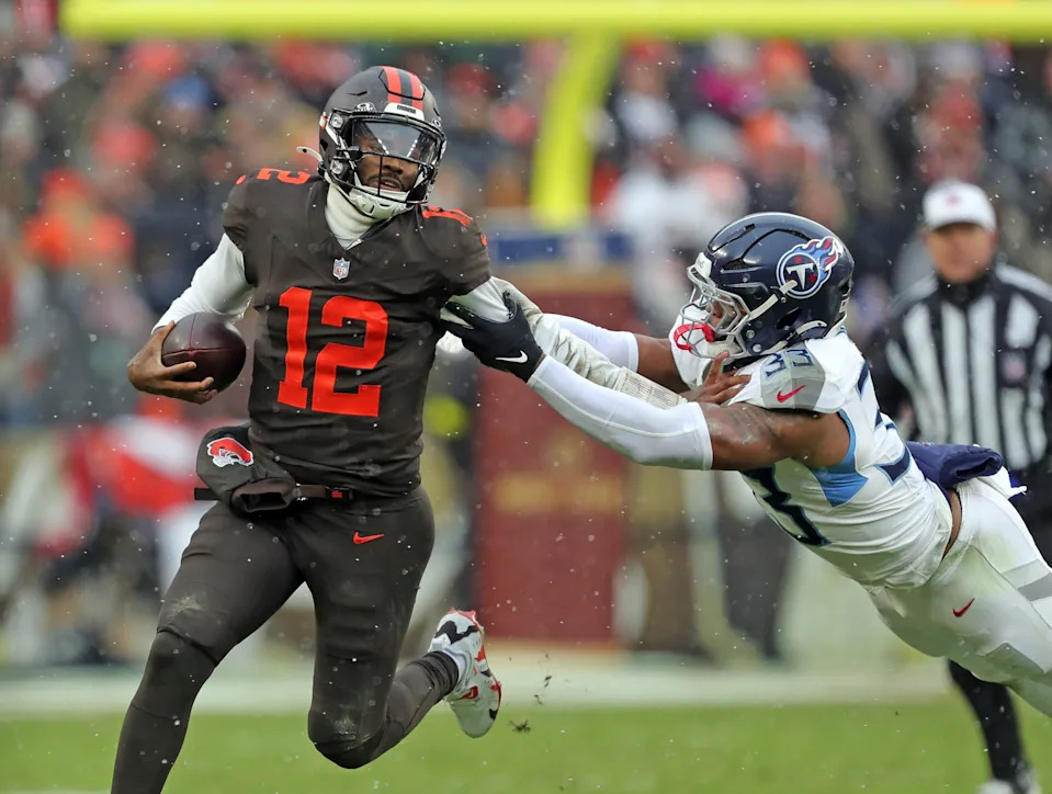 Cleveland Browns quarterback Shedeur Sanders (12) picks up a first down on his feet ahead of Tennessee Titans linebacker Cedric Gray (33) during the first half of an NFL football game at Huntington Bank Field, Dec. 7, 2025, in Cleveland, Ohio.