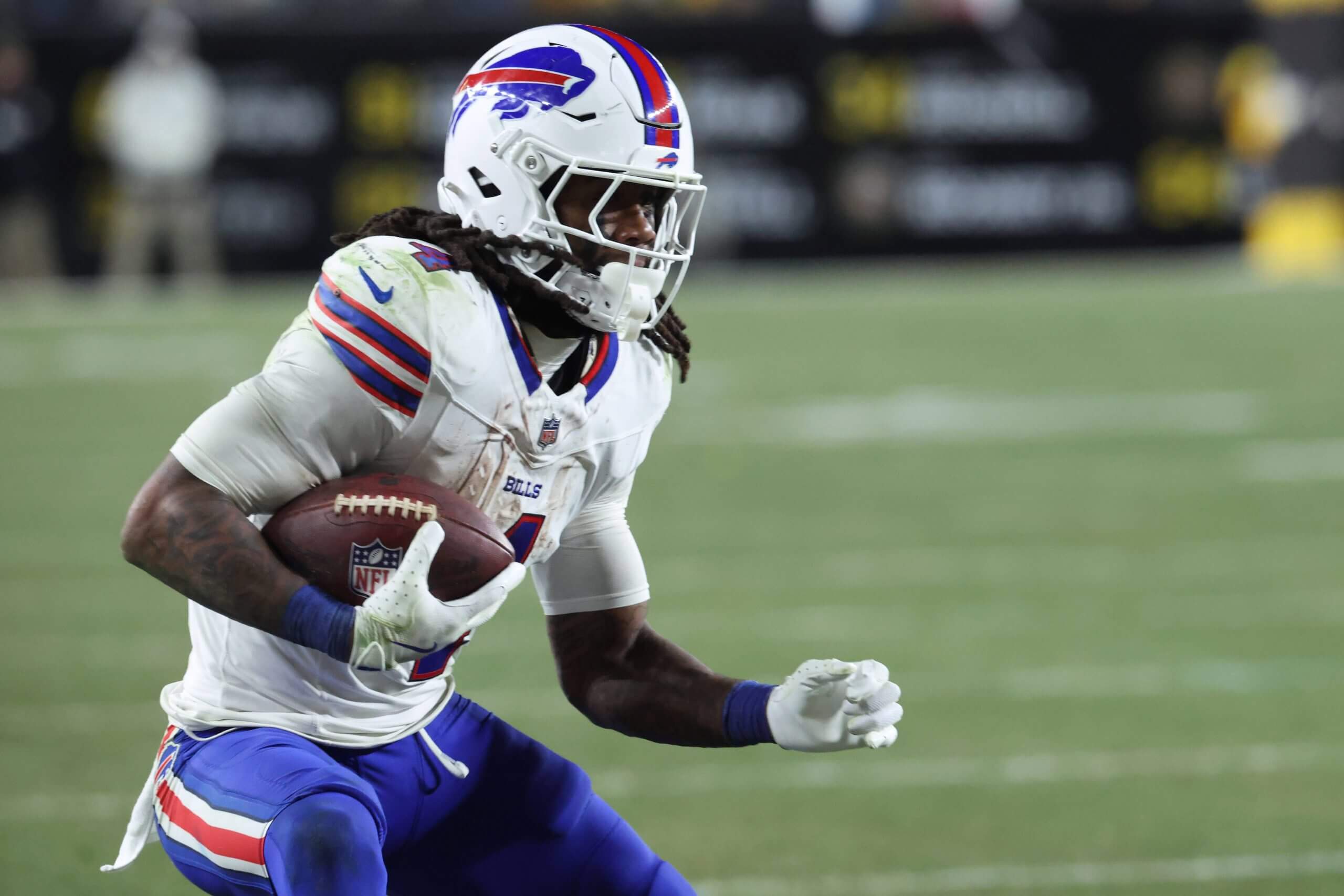 Bills running back James Cook holds the ball to his chest in his right hand in a ready stance on the field.